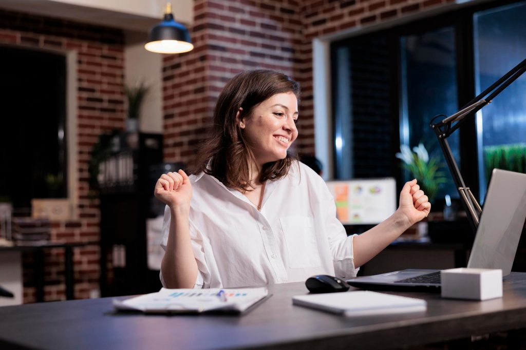 woman celebrates in front of computer