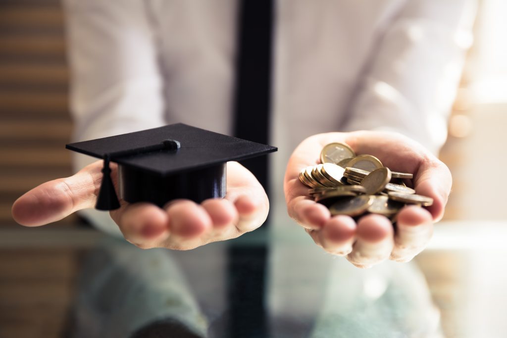 Human Hand Holding Graduation Hat And Golden Coins
