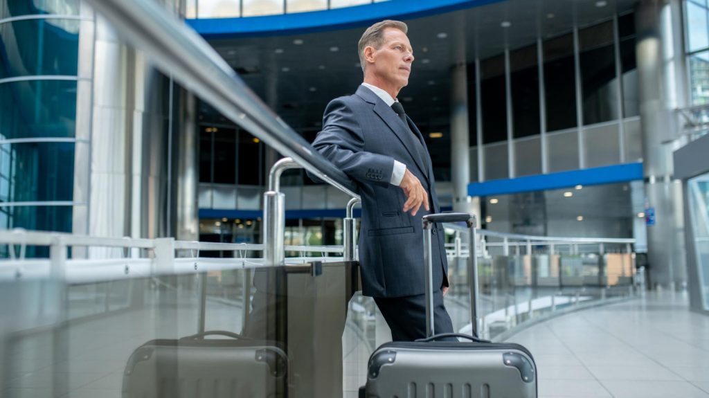 pensive businessman with suitcase standing airport