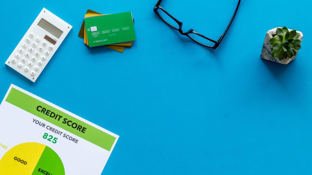 credit score with credit cards and calculator, glasses on banker work place blue background top view mock up.