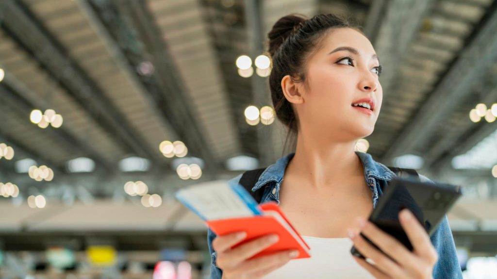 Woman at airport with Venture X rewards credit card travel benefits