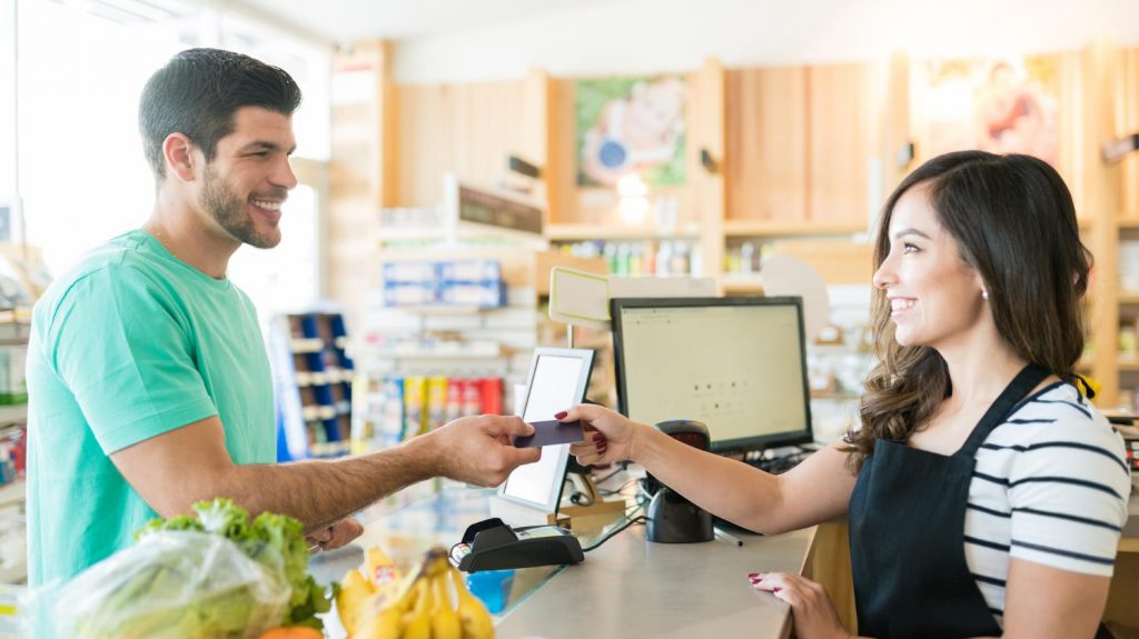 man using Huntington Bank Voice Rewards credit card at grocery store