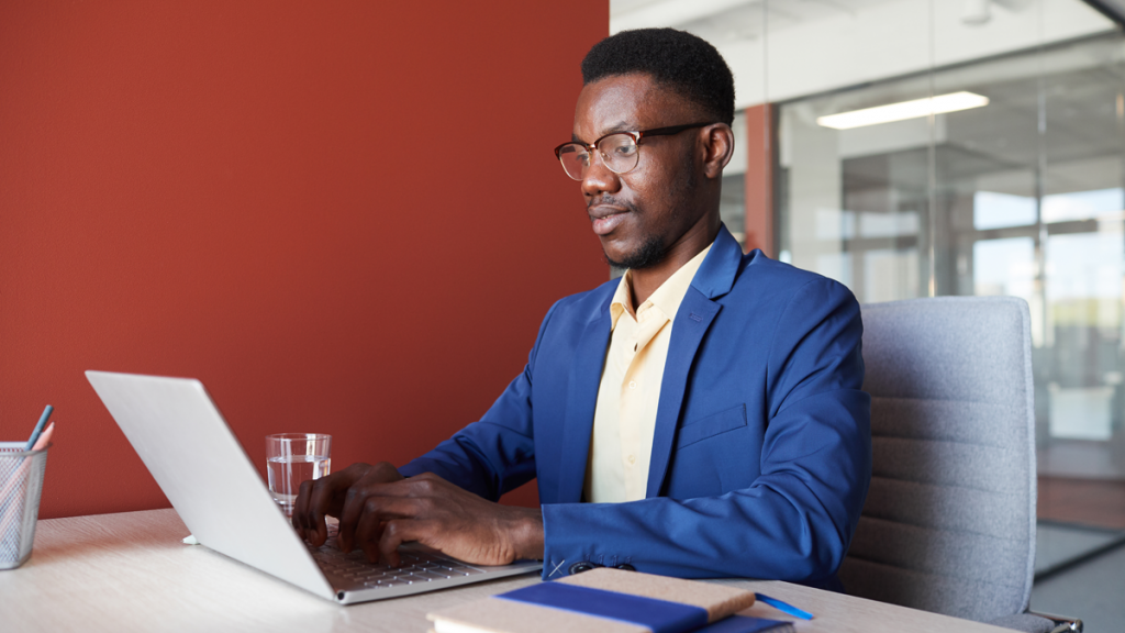 black man in business attire looking at his computer