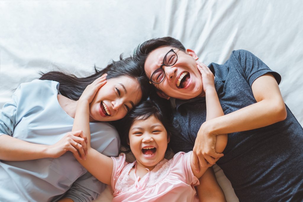 Happy Asian family laying on bed in bedroom with happy and smile